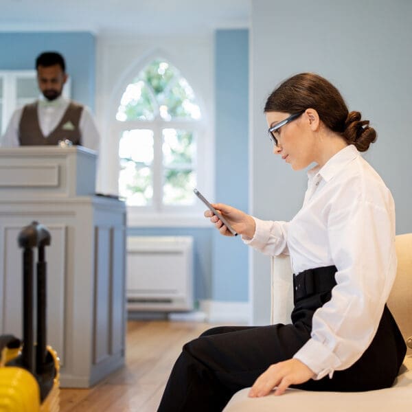 Businesswoman Using Smartphone Booking Room Sitting At Reception